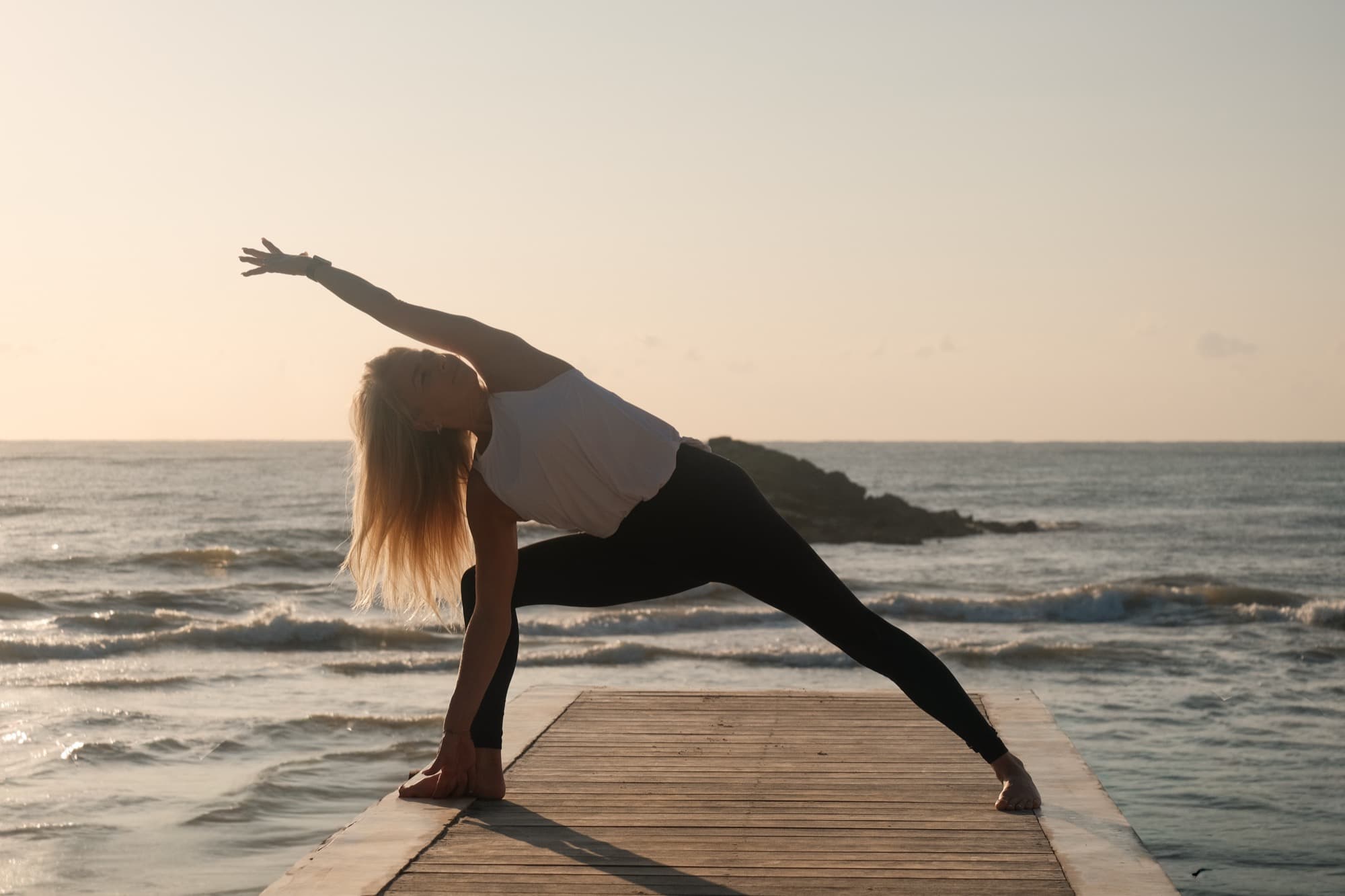 Gudrun in a yoga pose on a dock at sunset